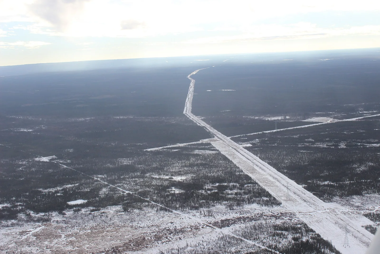 Aerial view of pipeline rights-of-way crossing a snowy forest