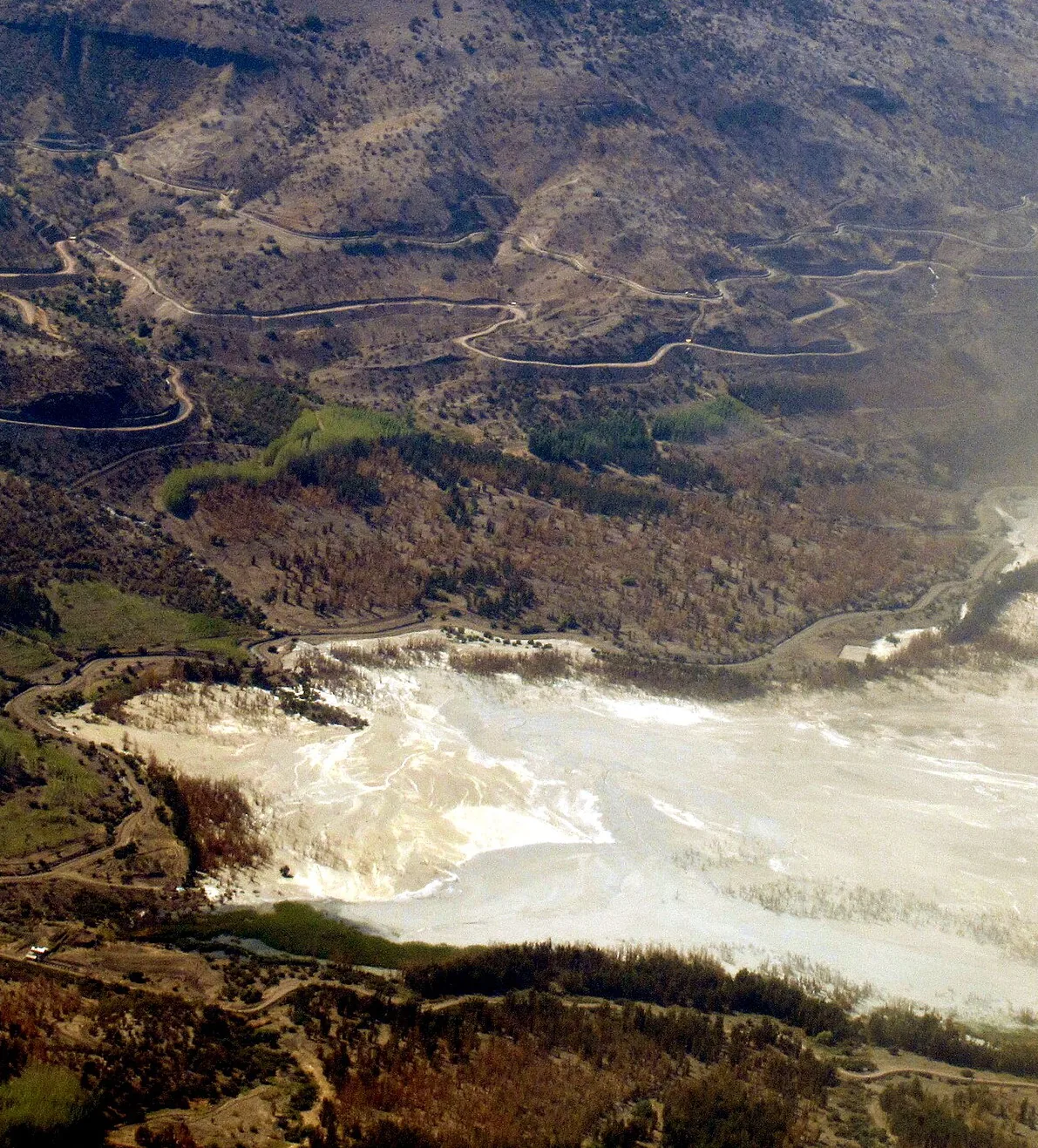 Aerial view of a tailings dam and its pond in a mountain valley
