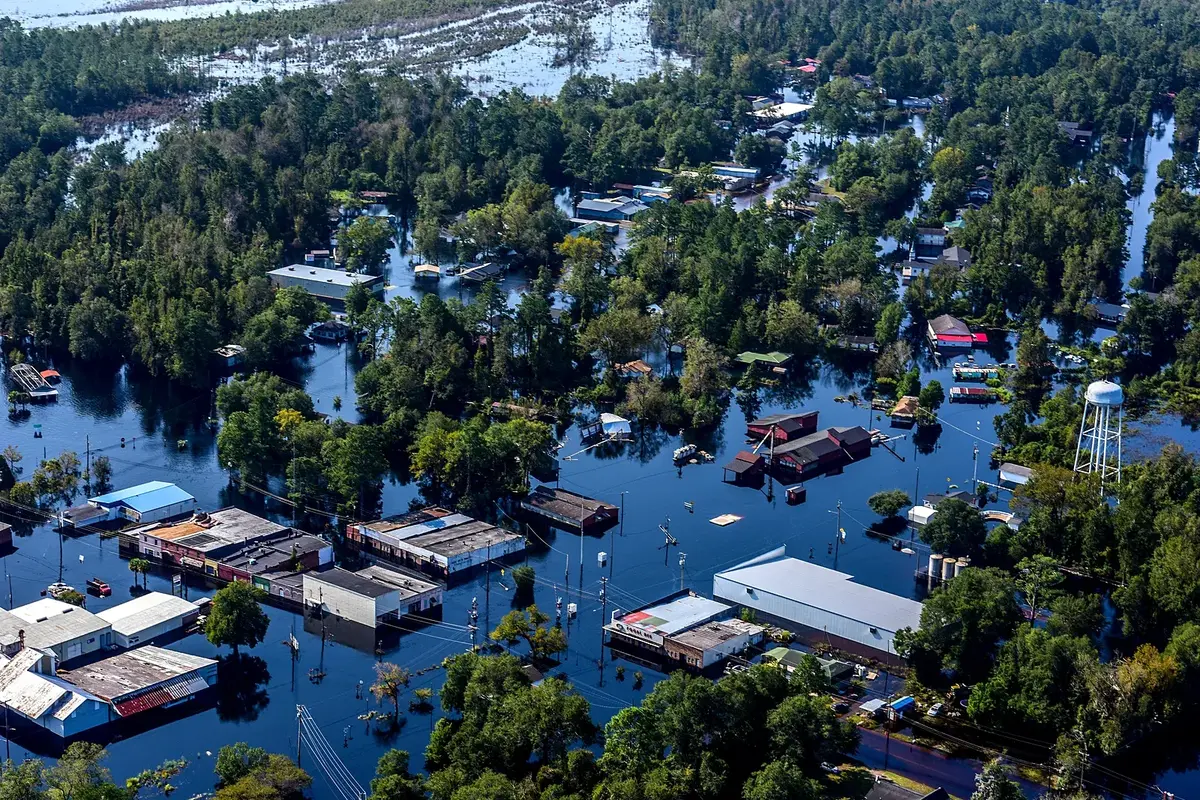Agua de inundación alrededor de viviendas y líneas de postes tras un huracán