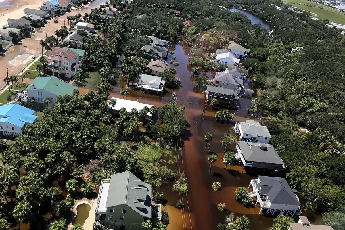 Una calle inundada con una línea de postes en pie dentro del agua tras un huracán