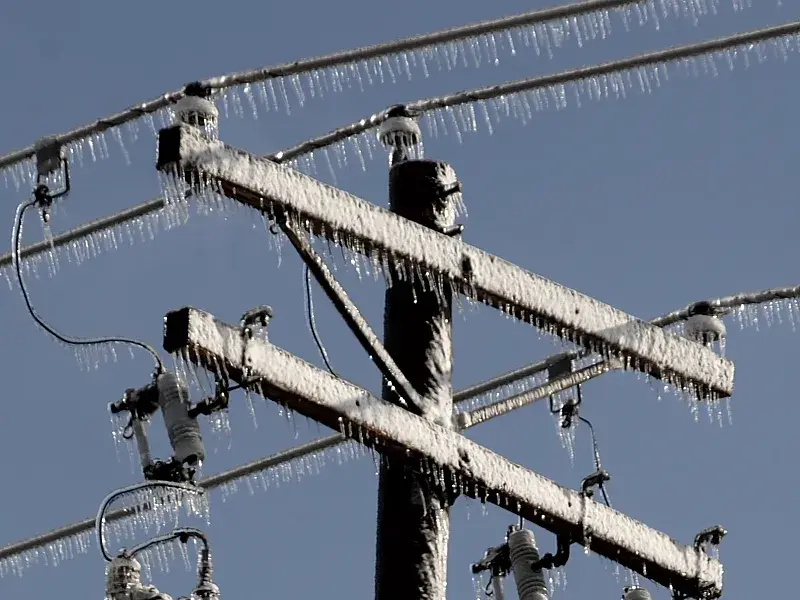 Un poste de distribución, sus crucetas y conductores cubiertos de hielo tras una lluvia engelante