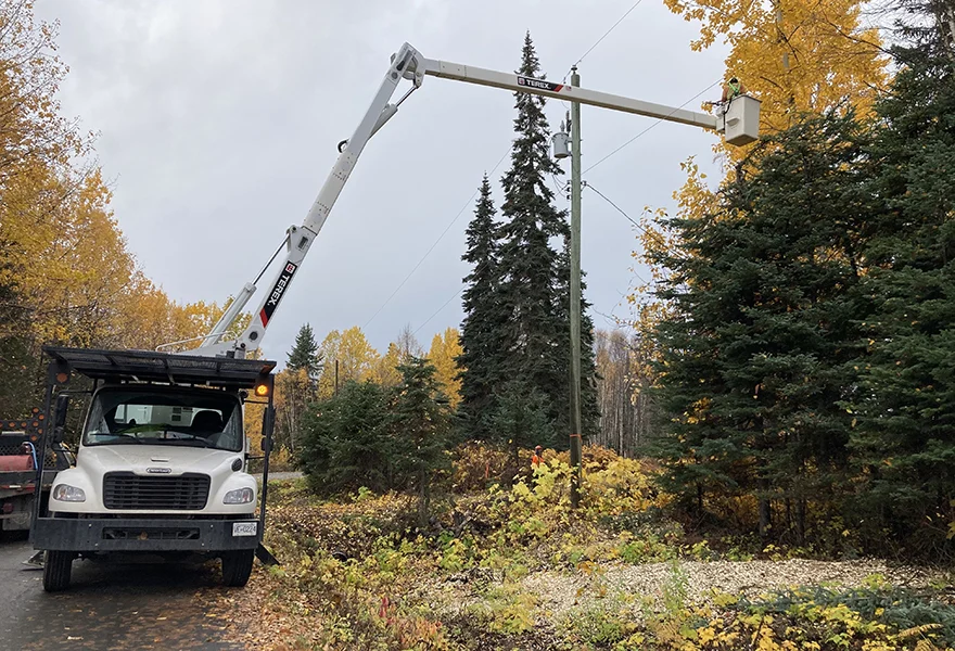 Bucket truck working on a power line among autumn trees
